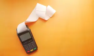 POS con scontrino lungo su sfondo arancione. Utile per una tabella costi deducibili professionisti.