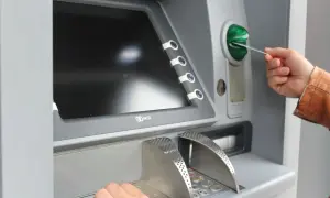 Mano inserisce una carta in un bancomat per versare contanti in banca.