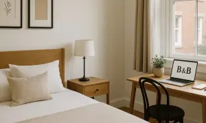 A B&B room with a bed, desk, laptop, and window.