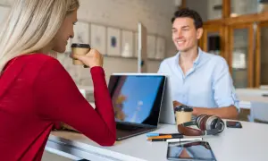 Due professionisti discutono strategie per come trovare clienti da libero professionista, sorseggiando caffè.