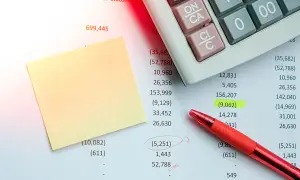 Foglio di calcolo con calcolatrice, penna rossa e post-it. Un esempio di rimborso spese in fattura evidenziato.