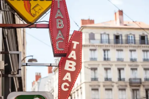 Insegne luminose di un tabaccheria, con la scritta "TABAC" in rosso e bianco. Qui si può acquistare anche una carta prepagata usa e getta.