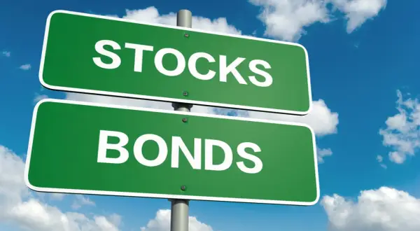Cartelli stradali verdi indicano "STOCKS" e "BONDS", illustrando la differenza tra azioni e obbligazioni.