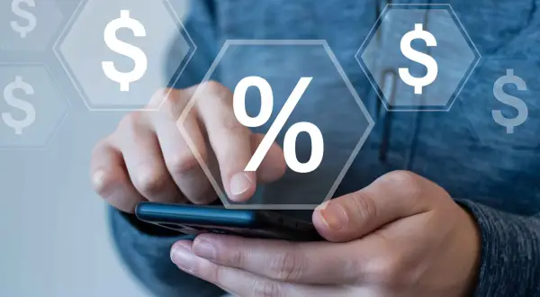 Mani che interagiscono con uno smartphone, con icone di dollari e un simbolo di percentuale che fluttuano, suggerendo il calcolo di cosa sono i premi assicurativi.