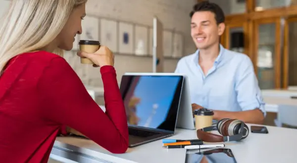 Due professionisti discutono strategie per come trovare clienti da libero professionista, sorseggiando caffè.
