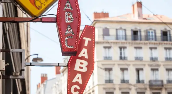 Insegne luminose di un tabaccheria, con la scritta "TABAC" in rosso e bianco. Qui si può acquistare anche una carta prepagata usa e getta.