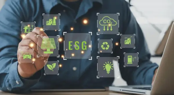 Un uomo interagisce con icone digitali che illustrano il **significato ESG in finanza**: energia solare, auto elettrica, riciclo, CO2, industria e lampadina.