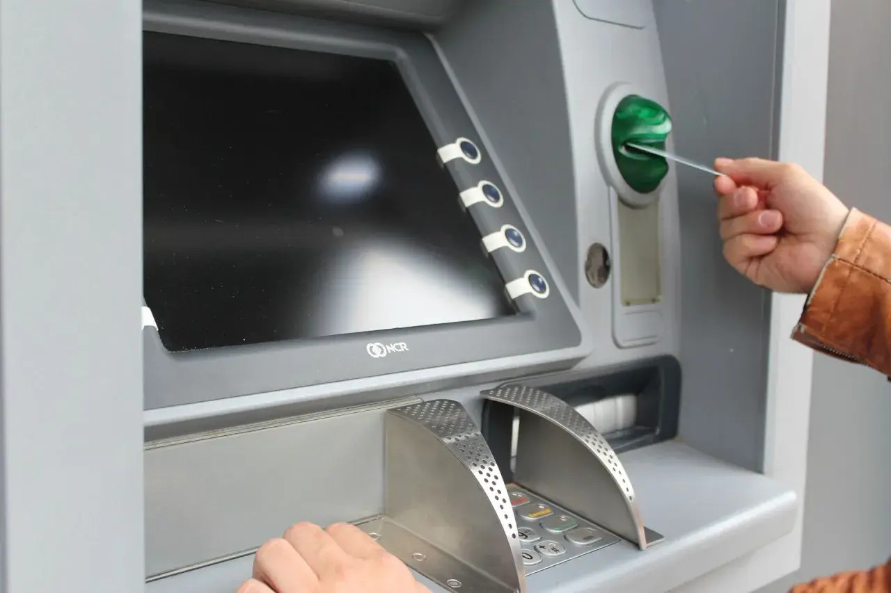 Mano inserisce una carta in un bancomat per versare contanti in banca.