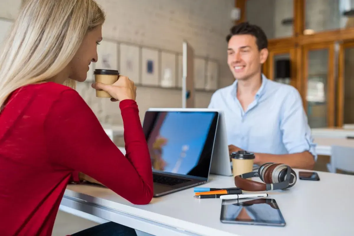 Due professionisti discutono strategie per come trovare clienti da libero professionista, sorseggiando caffè.