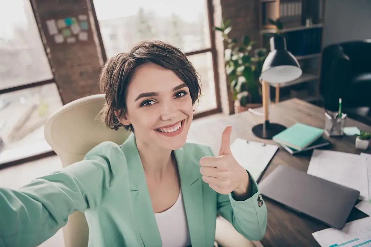 Libera professionista sorridente con pollice in su, pronta a scoprire come trovare clienti.