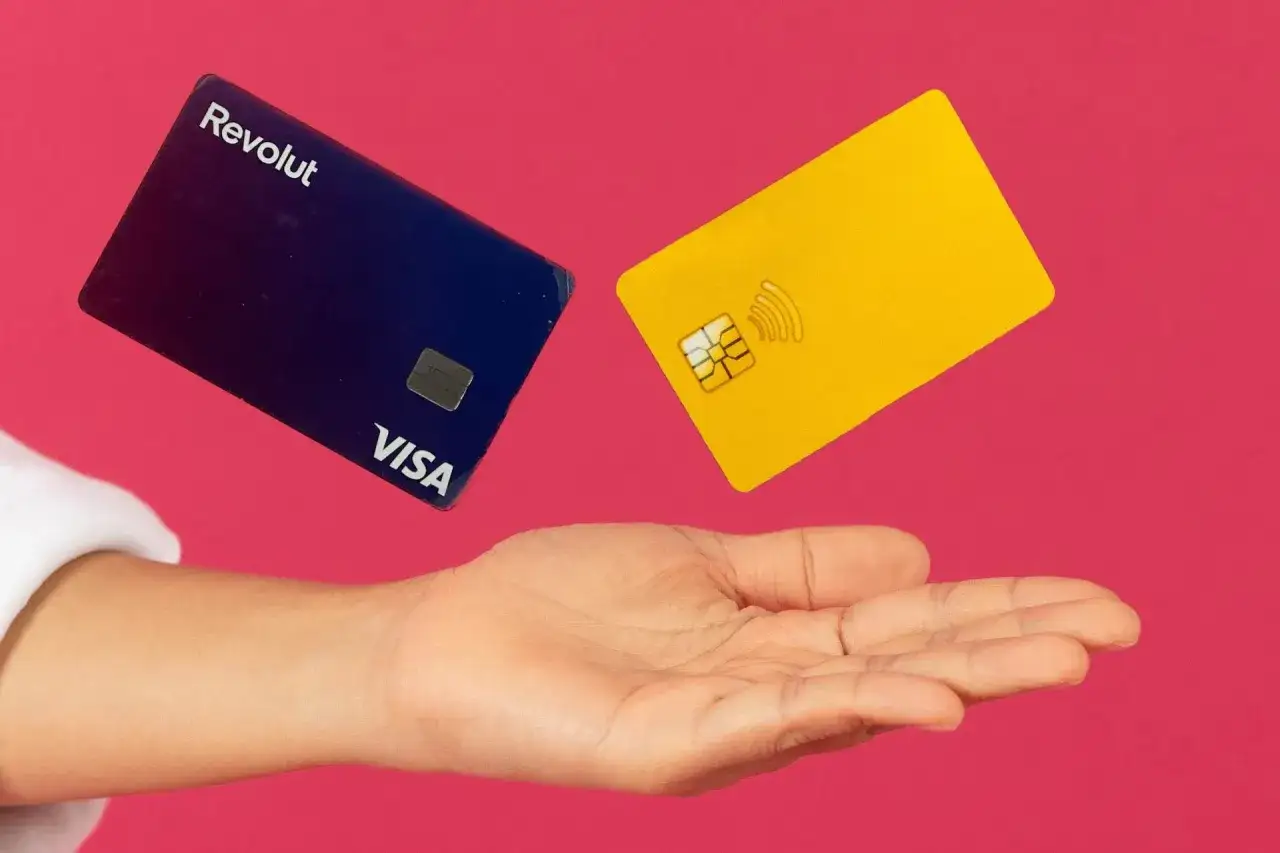 Due carte, una blu Revolut Visa e una gialla, fluttuano sopra una mano aperta. Capire la differenza carta credito e debito è fondamentale.