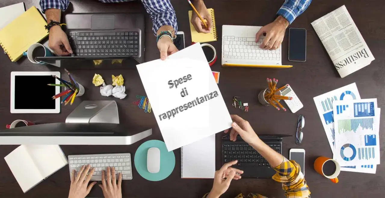Mani che lavorano su un tavolo pieno di strumenti d'ufficio, con un foglio che riporta