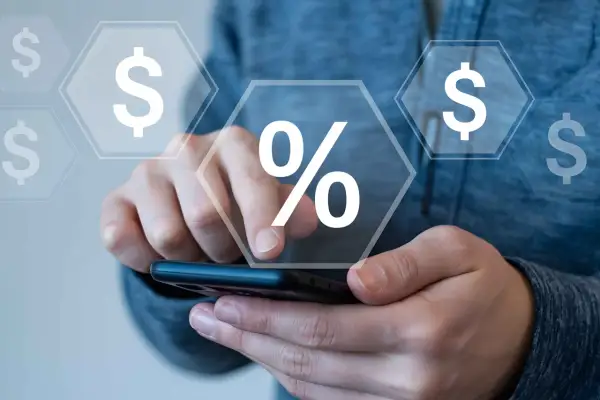 Mani che interagiscono con uno smartphone, con icone di dollari e un simbolo di percentuale che fluttuano, suggerendo il calcolo di cosa sono i premi assicurativi.