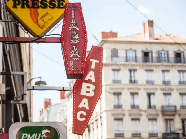 Insegne luminose di un tabaccheria, con la scritta "TABAC" in rosso e bianco. Qui si può acquistare anche una carta prepagata usa e getta.