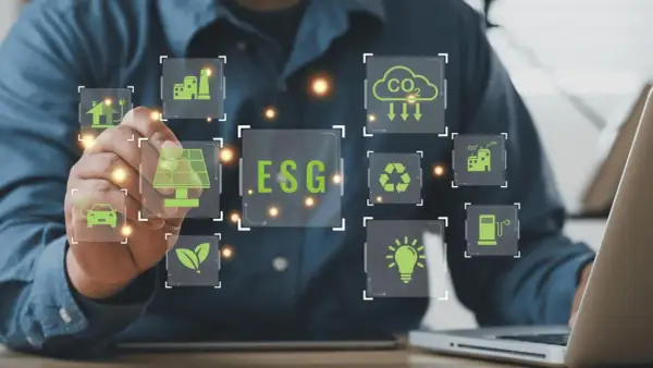 Un uomo interagisce con icone digitali che illustrano il **significato ESG in finanza**: energia solare, auto elettrica, riciclo, CO2, industria e lampadina.