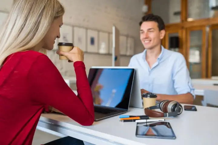 Due professionisti discutono strategie per come trovare clienti da libero professionista, sorseggiando caffè.